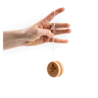 Zdjęcie: Na białym tle fragment ręki z zawieszonym na palcu jojo. Jojo jest okrągłe i drewniane. Na nim grawerowana gałązka dębu.