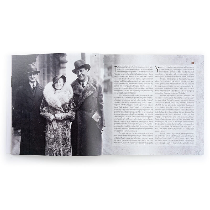 Zdjęcie: Na białym tle wnętrze książki. Na stronie lewej czarno-biała fotografia przedstawiająca kobietę w towarzystwie dwóch mężczyzn. Na stronie prawej dwie kolumny tekstu - jedna w języku polskim, druga w języku angielskim.