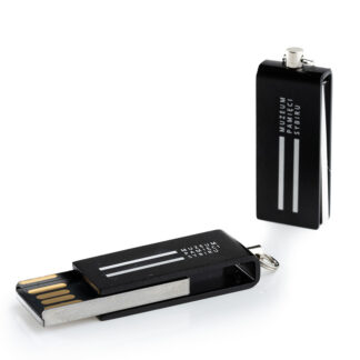 Zdjęcie: Na białym tle dwie, czarne pamięci USB z logo Muzeum Pamięci Sybiru.. Jedna pamięć ma wysunięty czytnik, druga, stojąca obok, ma czytnik schowany.